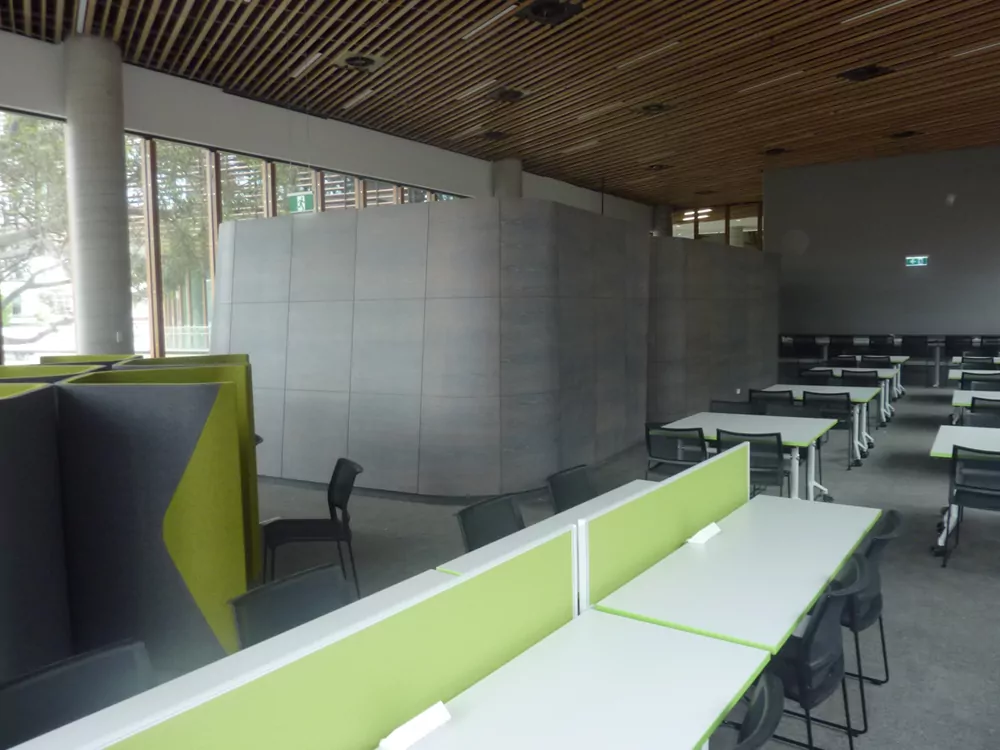 The interior of the University of Sydney's Business School. Green dividers separate seats and tables for students.