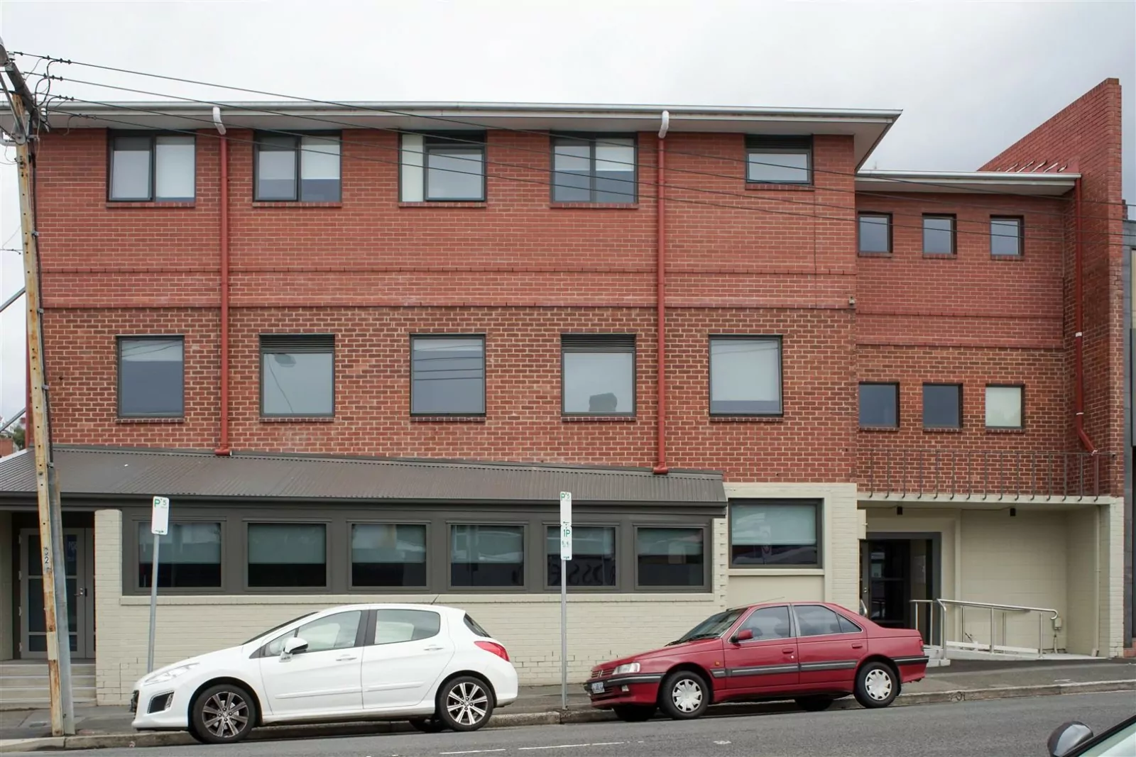 The two floors redbrick building, that was formerly the Waratah Hotel and bottleshop, providing medium-to-long-term crisis accommodation at Murray Street, Hobart. Two cars are parked outside on the street in front of the building.