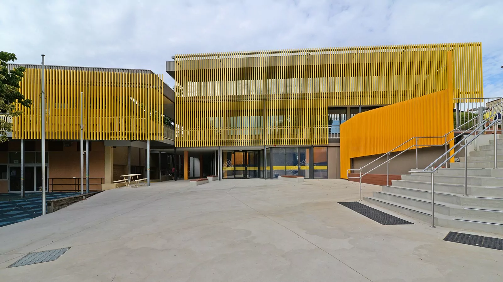 The revitalised Girton Grammar d'Helin Building. The building features an architectural screen which adds shade and colour to the facade, timber seating and stair access to the admin forecourt.