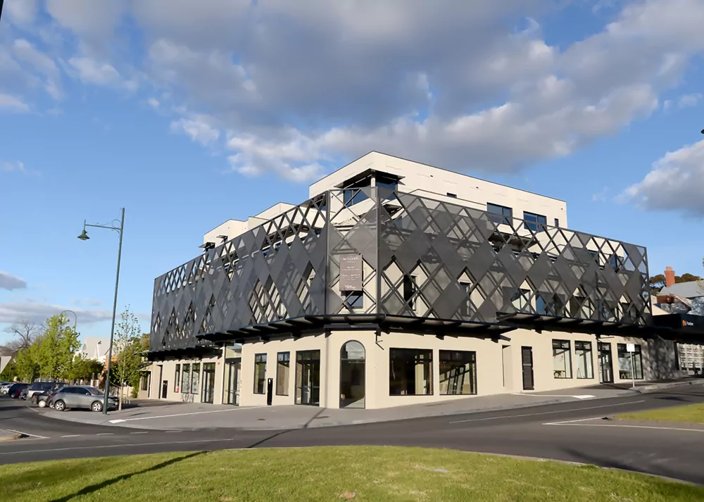 A streetview of the modern mixed use development 111 Mitchell Street building in central. Metal cladding in checkered patterns contrasts pleasantly against the concrete building.