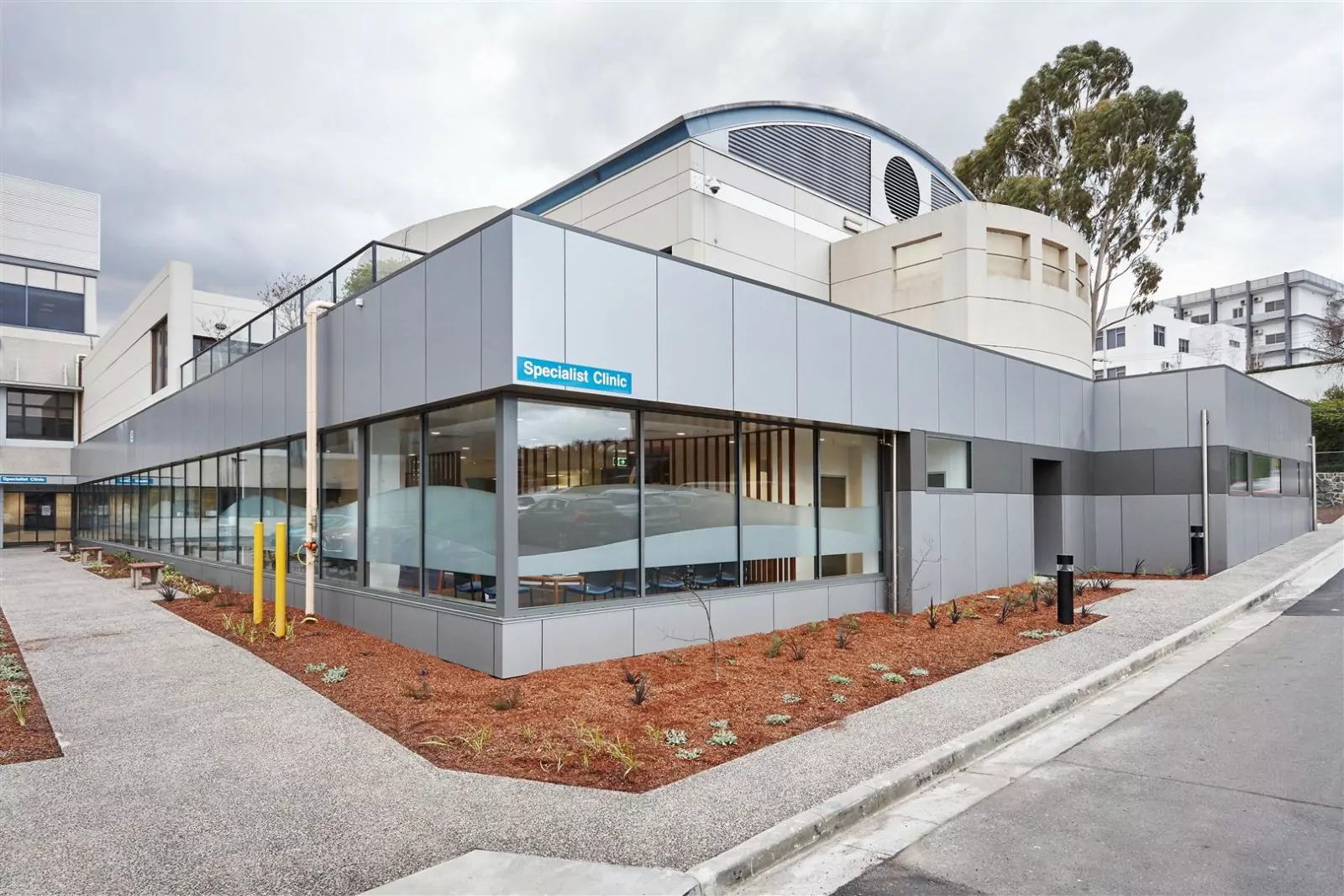 A pavement runs the perimeter of the Launceston General Hospital Specialist Clinic. The refurbished building is a new state-of-the-art 23-room building. The building features windows with privacy frosting and subtle blue signage.