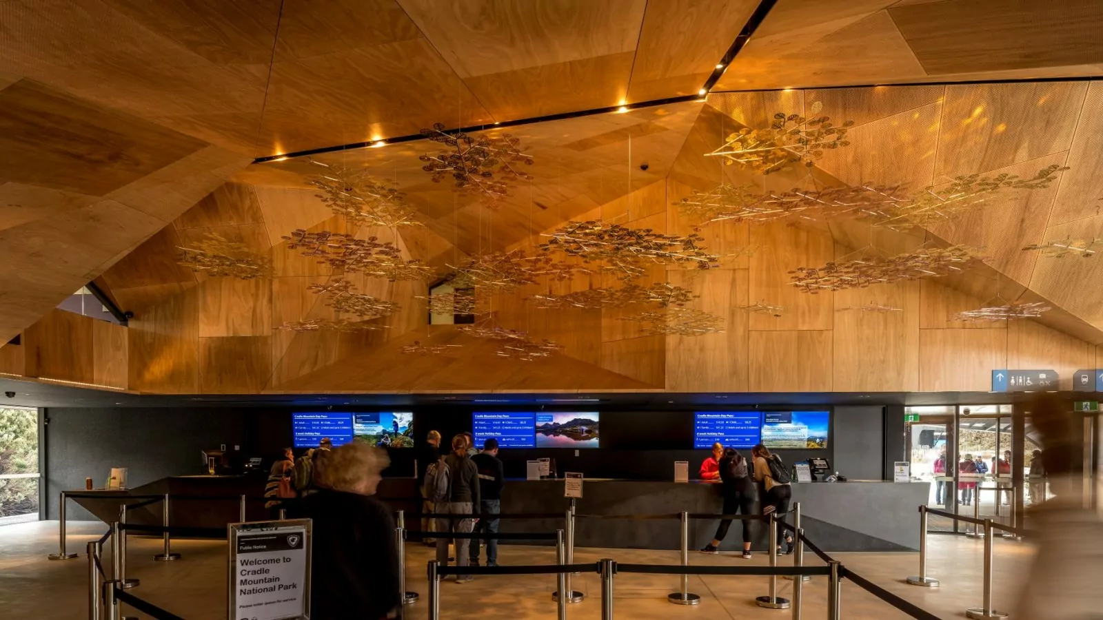 A photo of visitors that are queued and receiving customer service at the Cradle Mountain Gateway. People are also waiting outside.