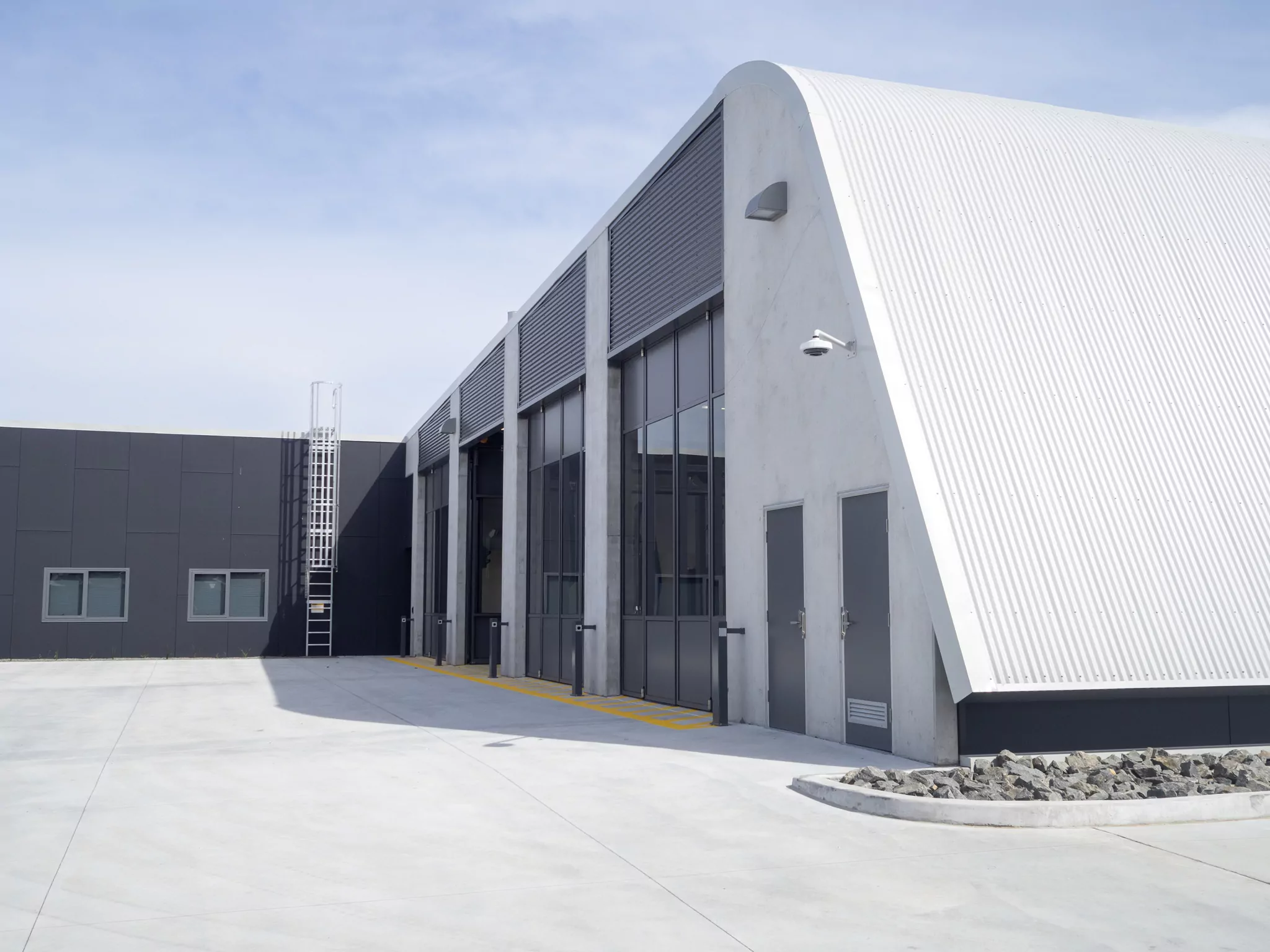 A satisfying match of grey clouds matches the concrete grey slopping building of the Sorell Emergency Services Hub. Tall doors allow the entry of emergency vehicles .