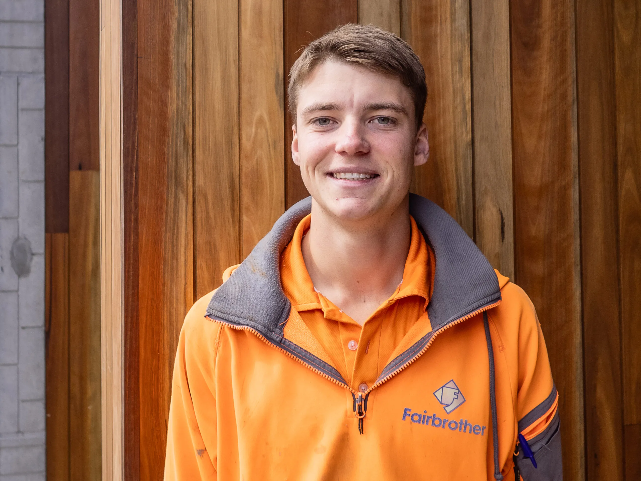 Cameron Direen, Fairbrother's 2023 Apprentice of the Year dressed in Fairbrother-branded hi vis standing in front of a natural timber facade.